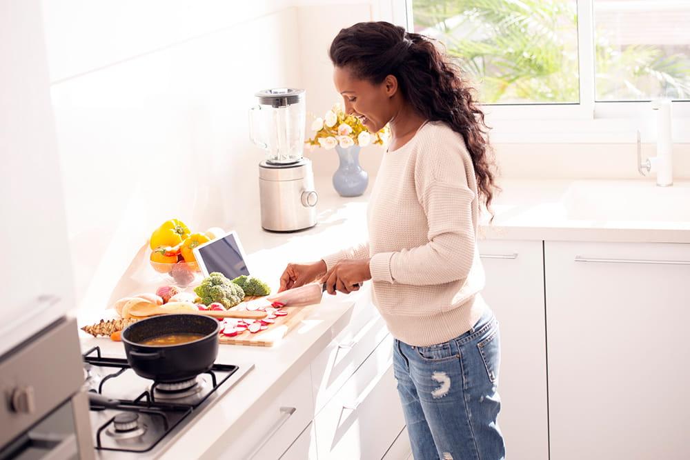 女人切食物放进炉子上的锅里